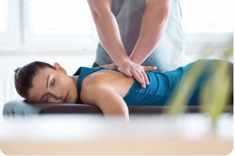 Frau erhält Rückenmassage auf Massageliege in Wellness-Praxis, Entspannung