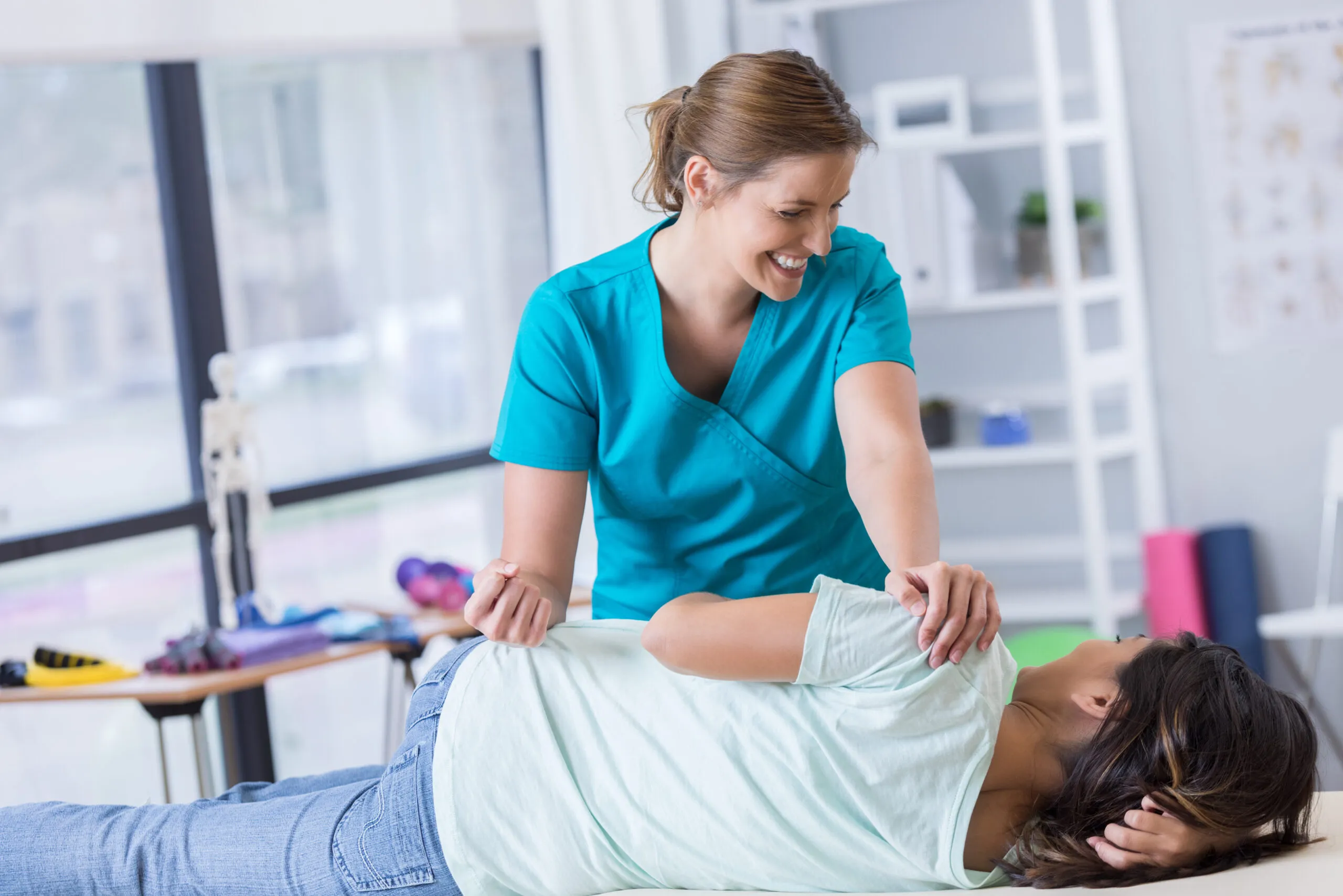 Physiotherapeutin behandelt Patientin mit Schultertherapie in Praxisraum